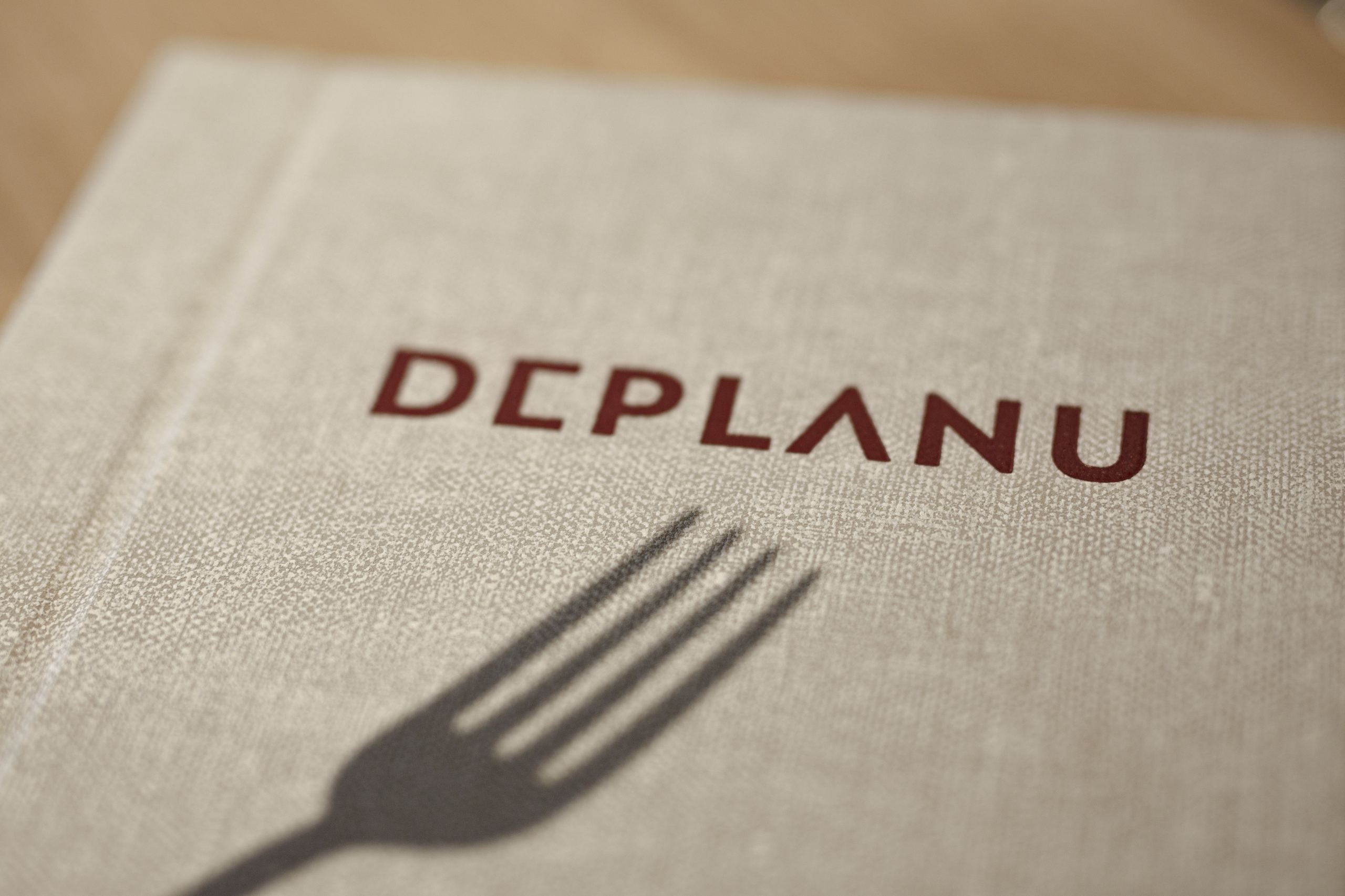 Menukaart met deplanu logo met een schaduw van een vork